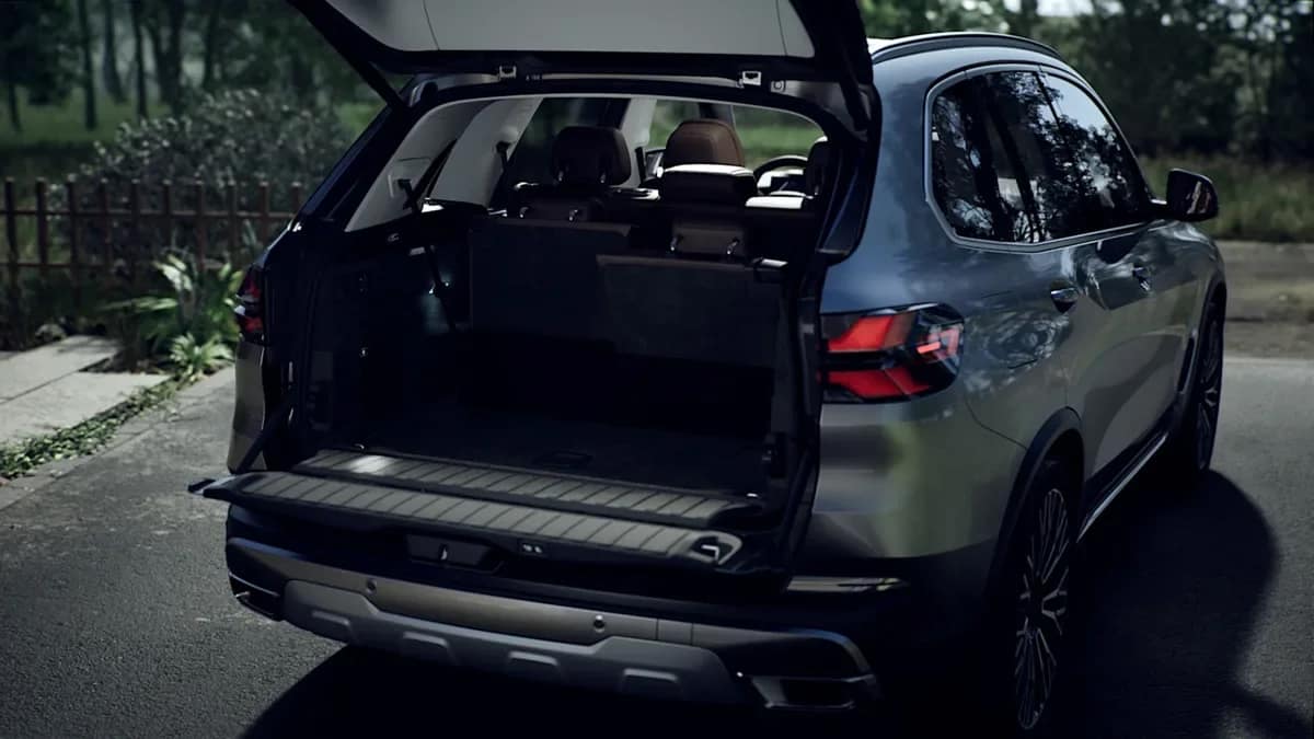 Open boot of the BMW X5 with its split tailgate, parked on a forest road