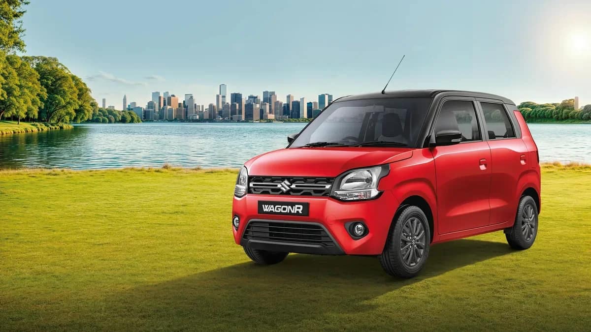 Red Maruti Suzuki WagonR with a black roof, the model sold in India today, parked on grass by a lake