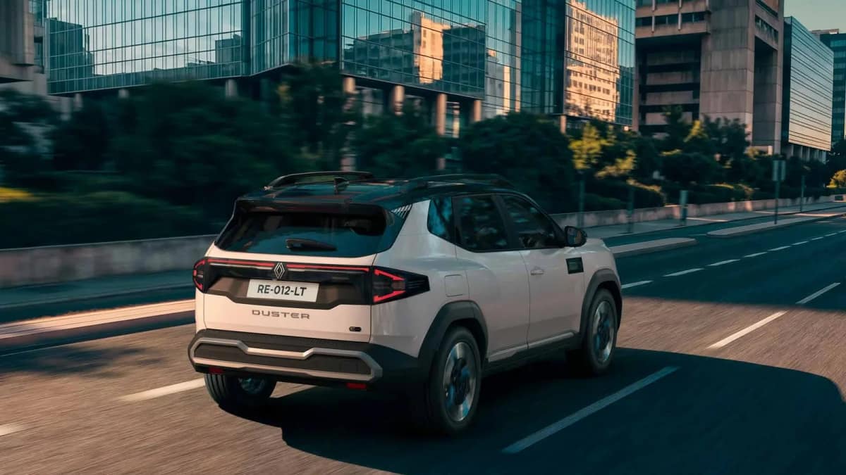 Rear view of the Renault Duster hybrid driving past glass office buildings