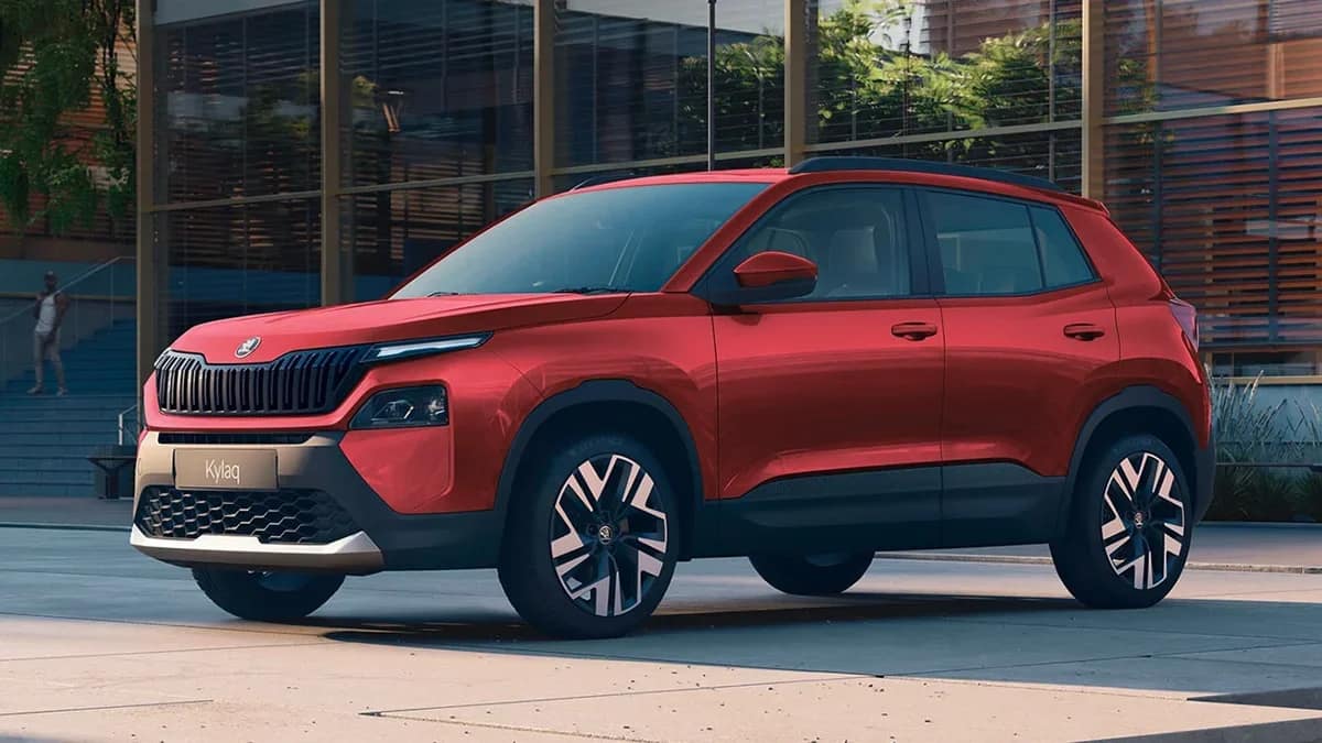 Front three quarter view of a red Skoda Kylaq SUV in front of a glass building