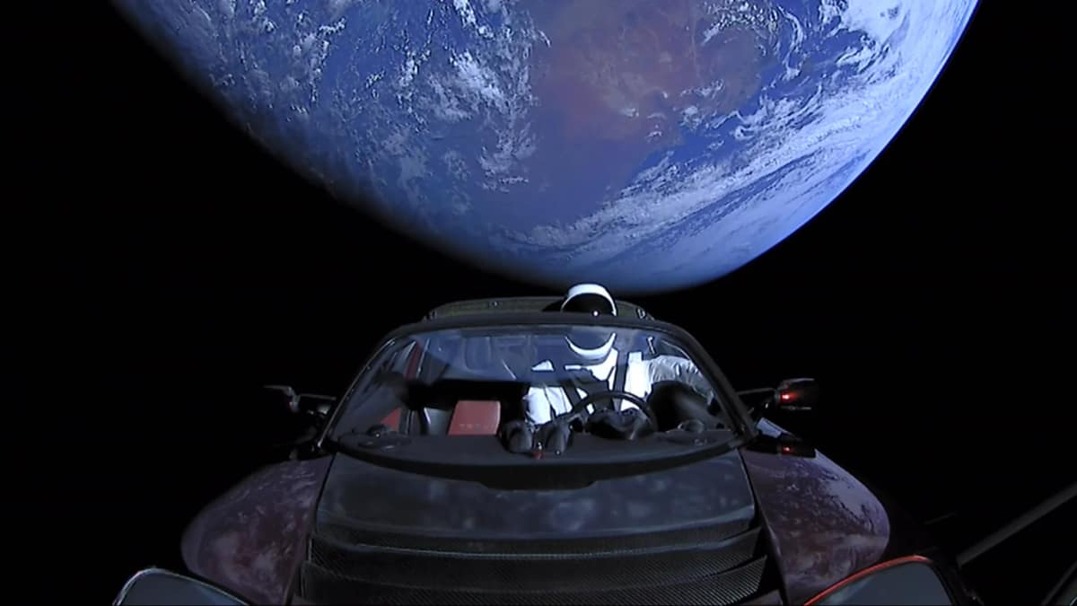 Tesla Roadster in space with Earth behind it and a mannequin in a SpaceX spacesuit in the driver's seat