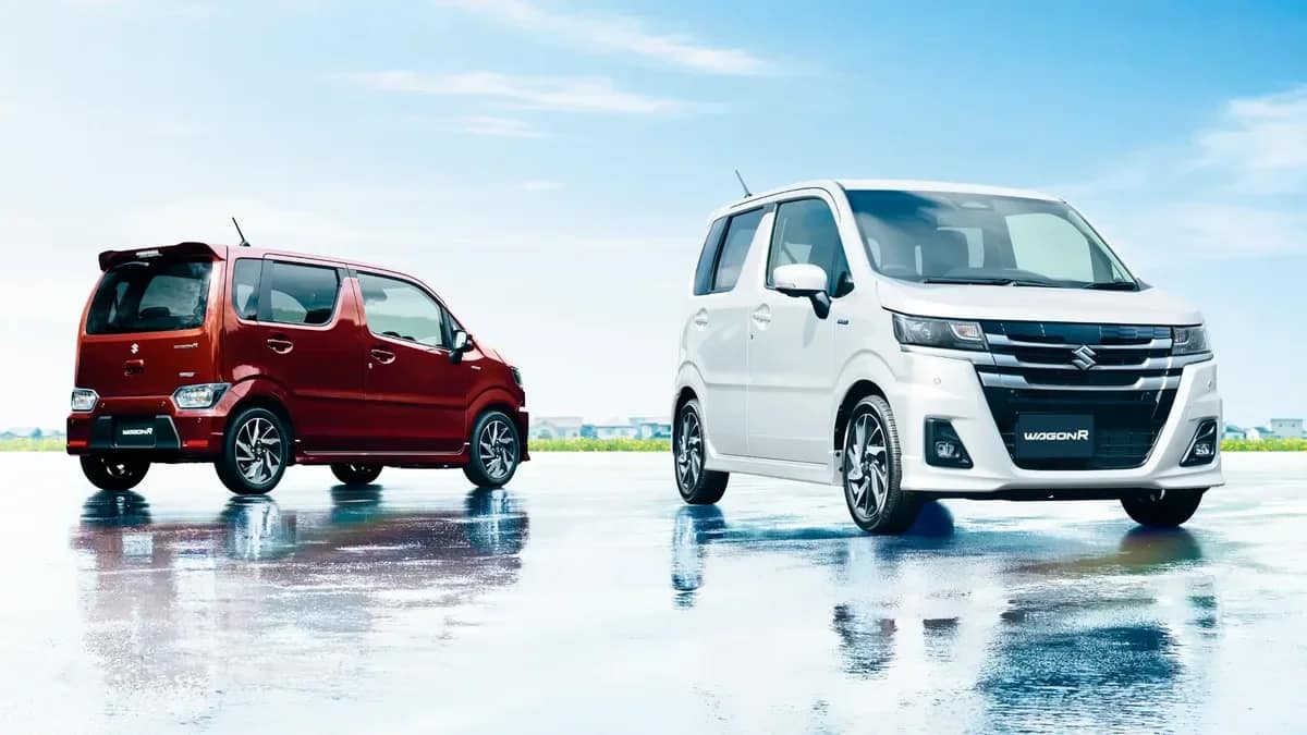 A red and a white Suzuki WagonR from Japan parked side by side on a wet road