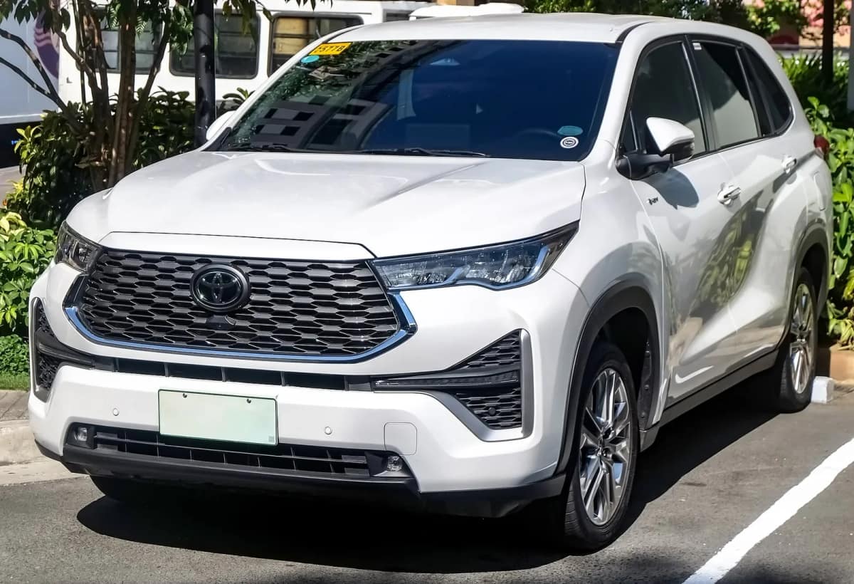White Toyota Innova Hycross type MPV seen from the front with a large honeycomb grille