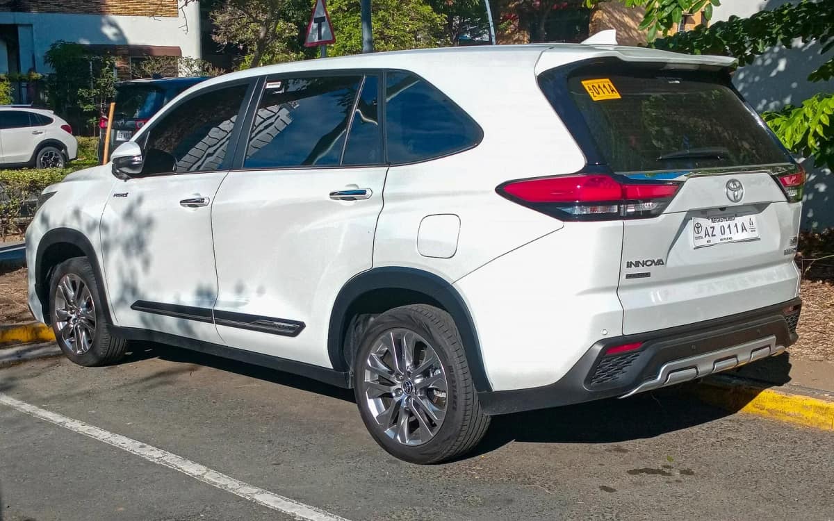 Rear three-quarter view of a white Toyota Innova Hycross type hybrid MPV